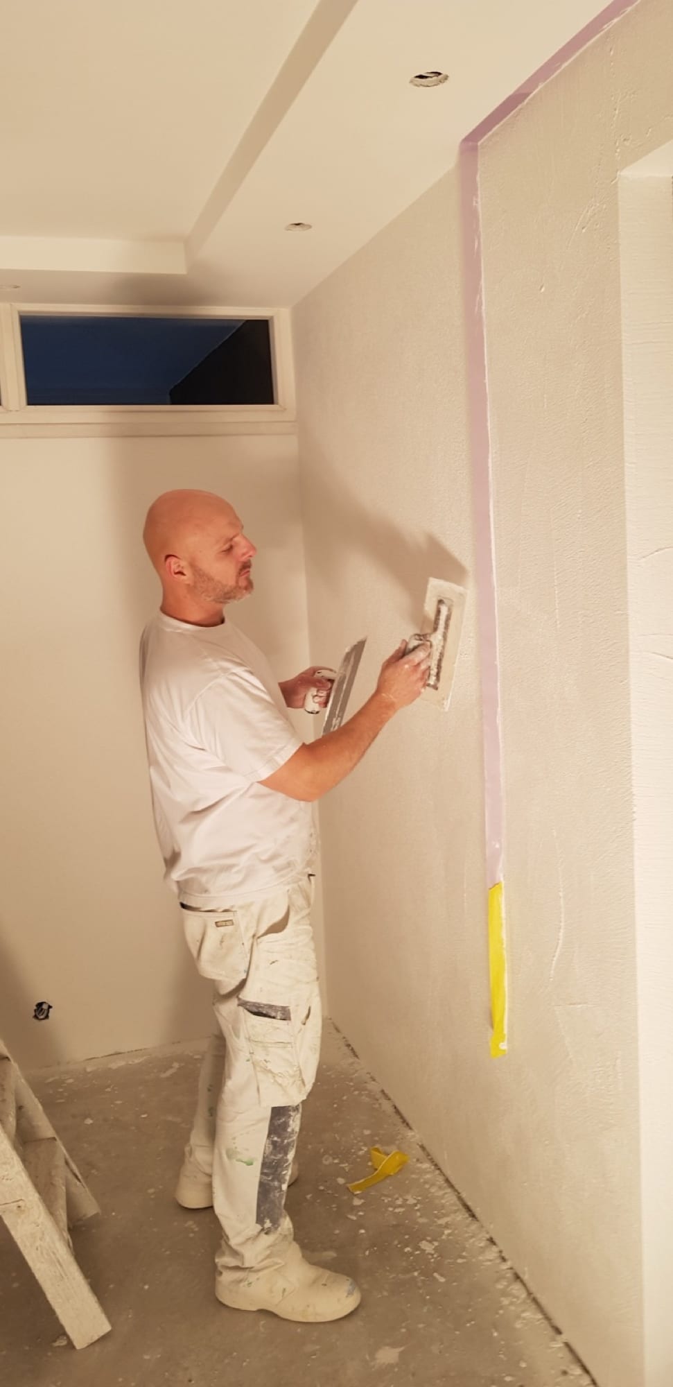 Stukadoor werkt de wand af met twee spanen tegelijk