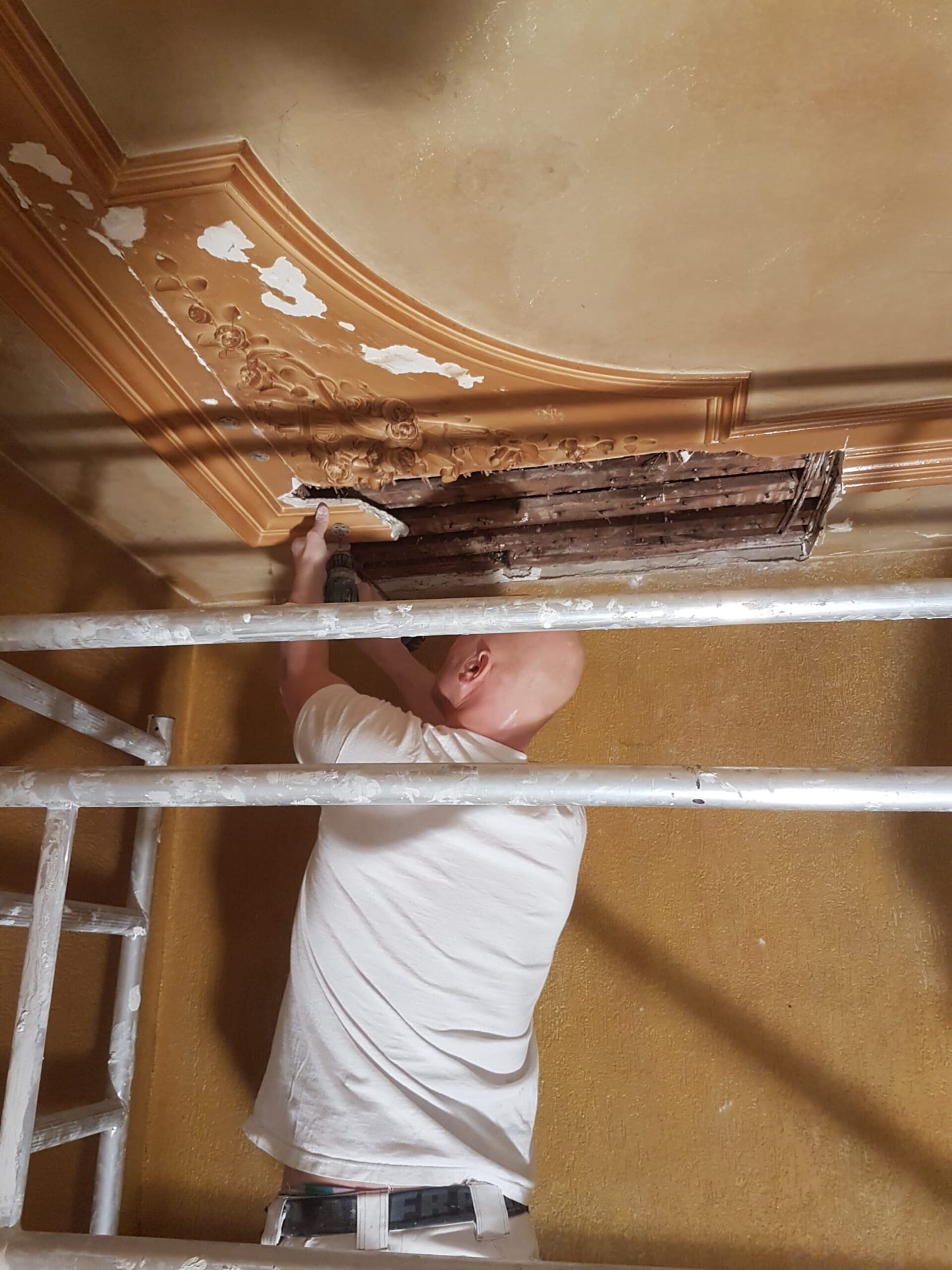 Stukadoor herstelt vanaf de steiger een monumentaal ornamentenplafond