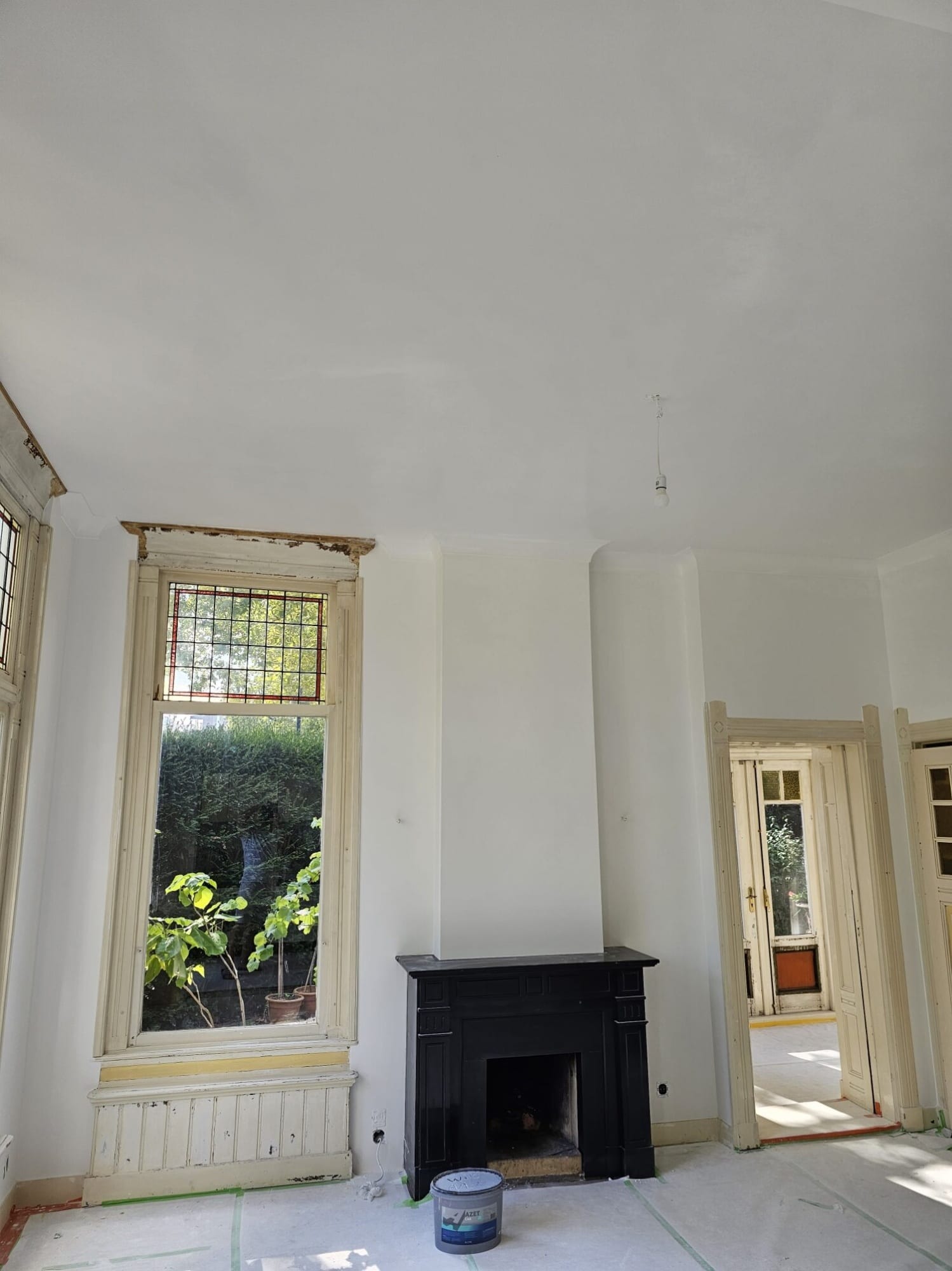 Strak wit plafond en wanden rond een klassieke schouw, net opgeleverd