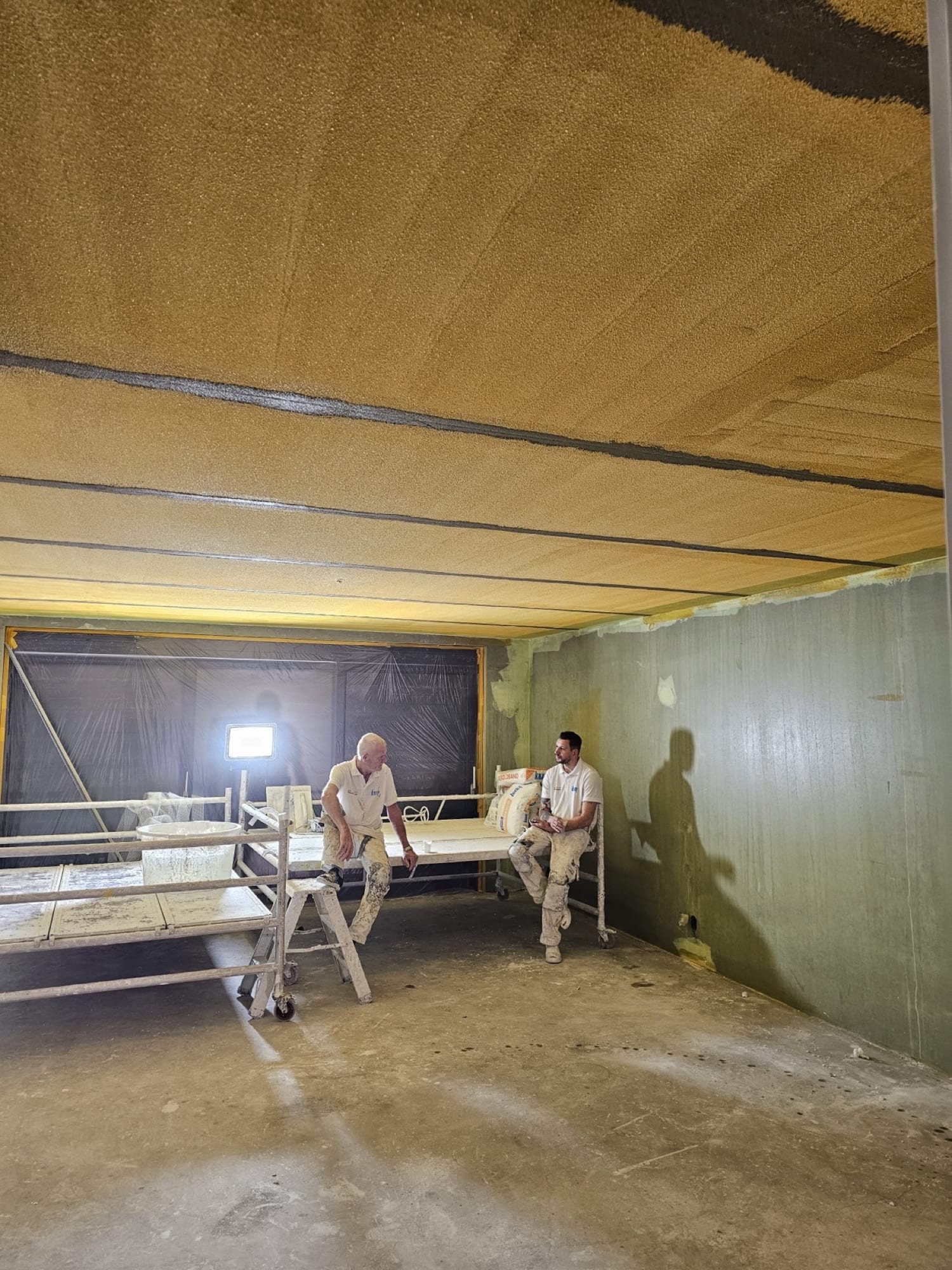 Twee stukadoors in de woonkamer voor het stuken, de wanden zijn nog kaal