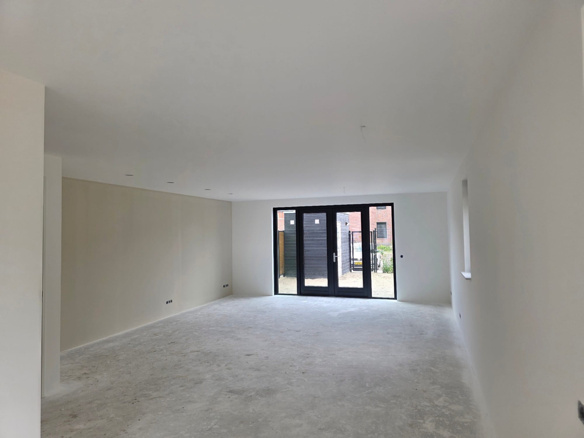 Strak gestuukte woonkamer van een nieuwbouwwoning met openslaande tuindeuren