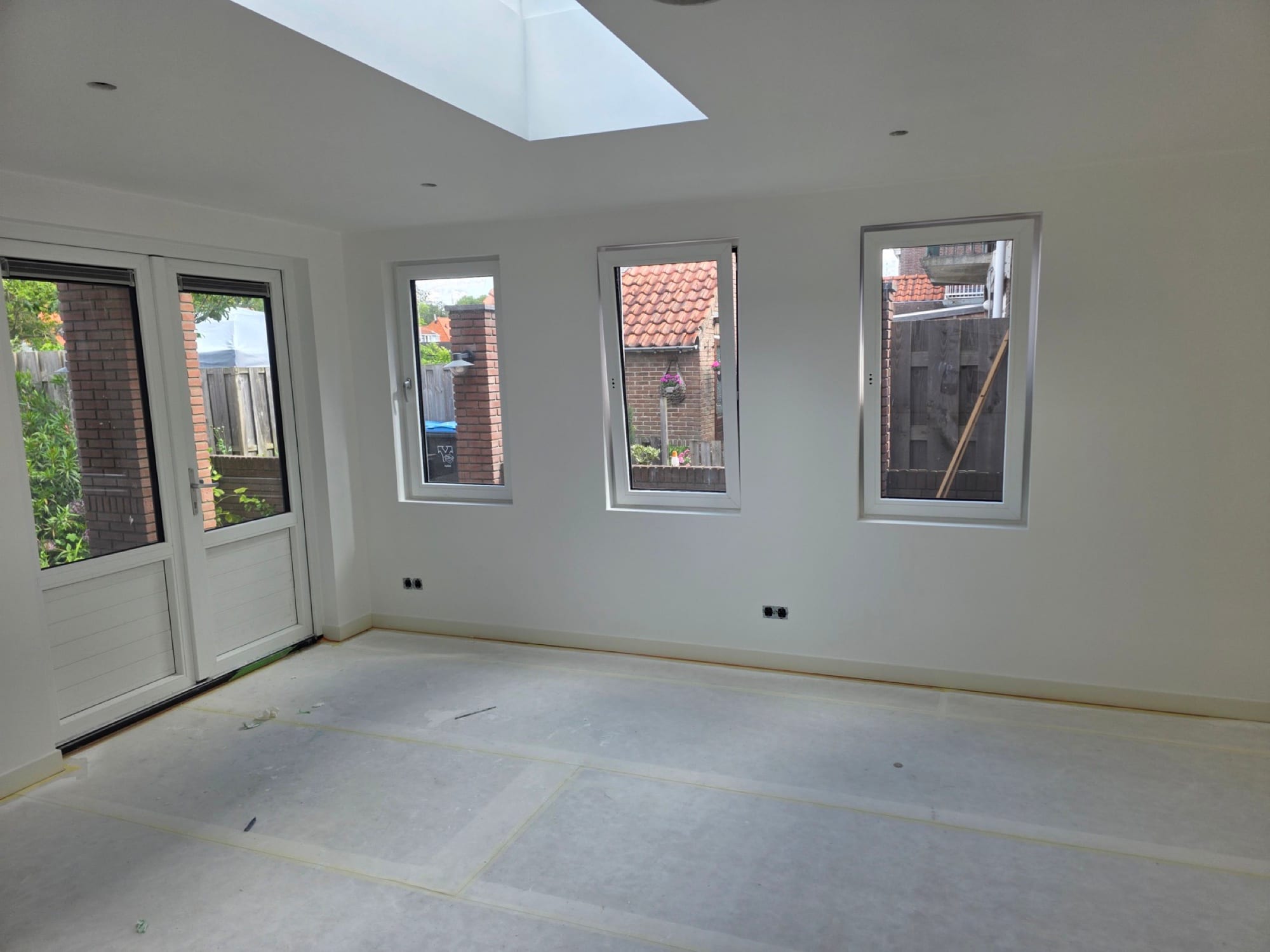 Afgewerkte, strak gestuukte kamer met openslaande tuindeuren en veel daglicht