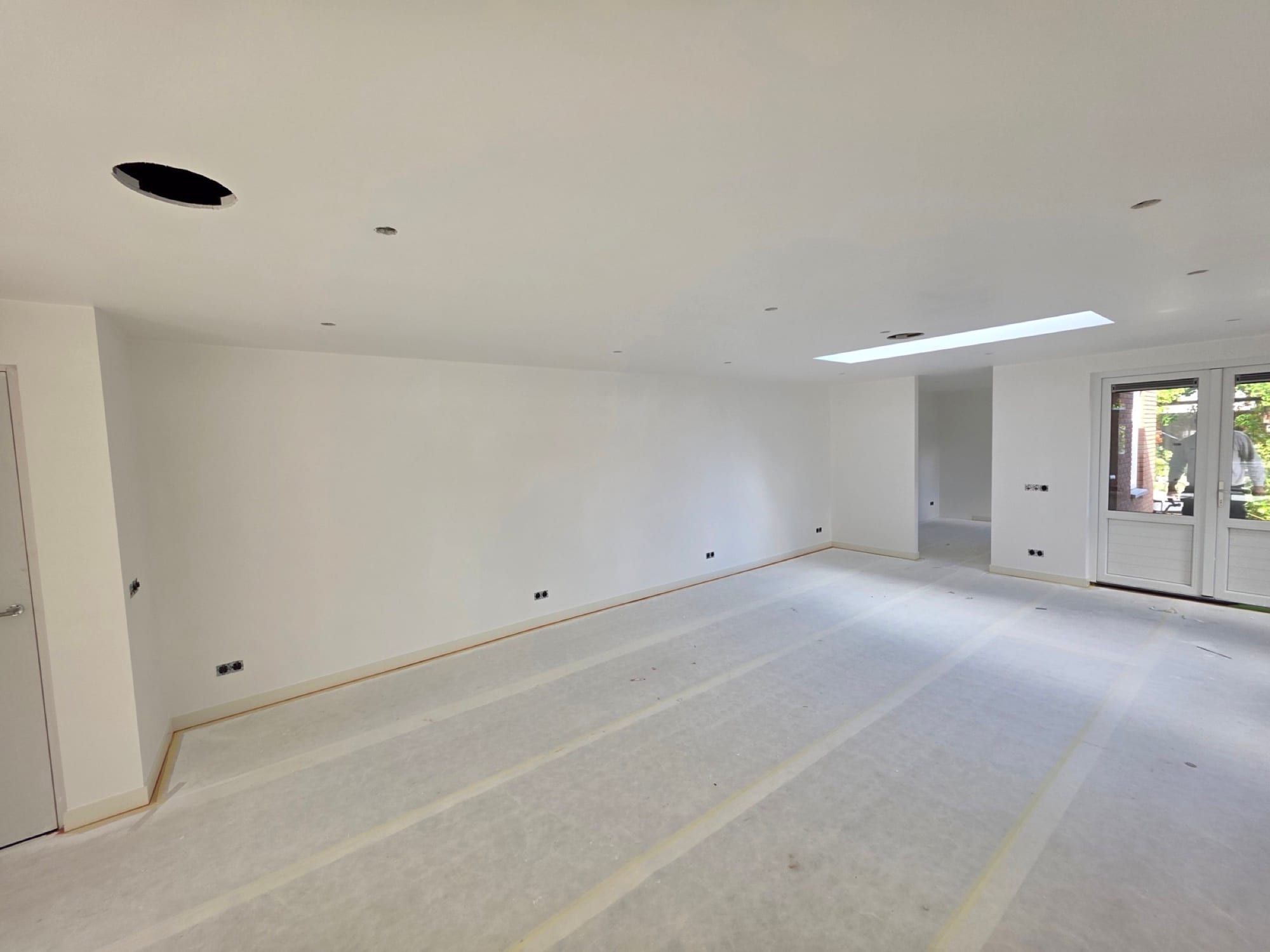 Ruime woonkamer met strak wit stucwerk op wanden en plafond