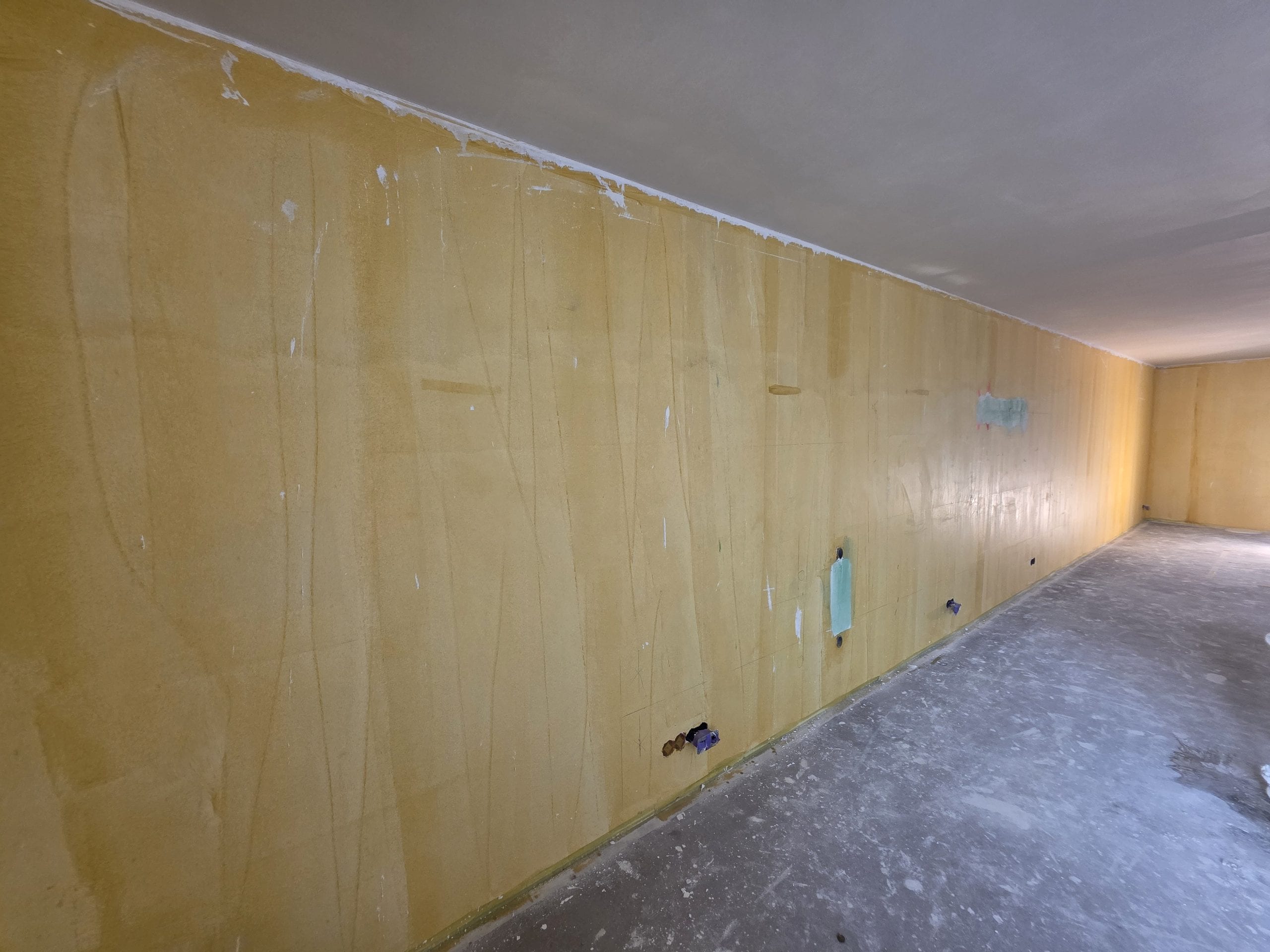 Lange voorgestreken wand met een al gestuukt plafond erboven