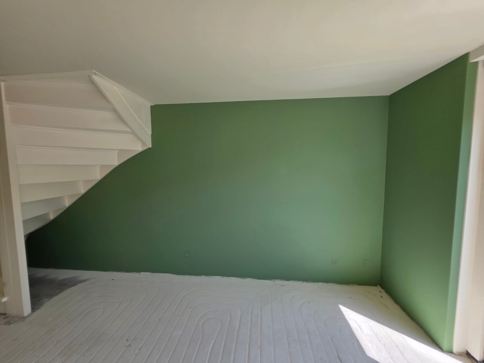 Groene accentwand onder de witte trap, strak sauswerk zonder strepen