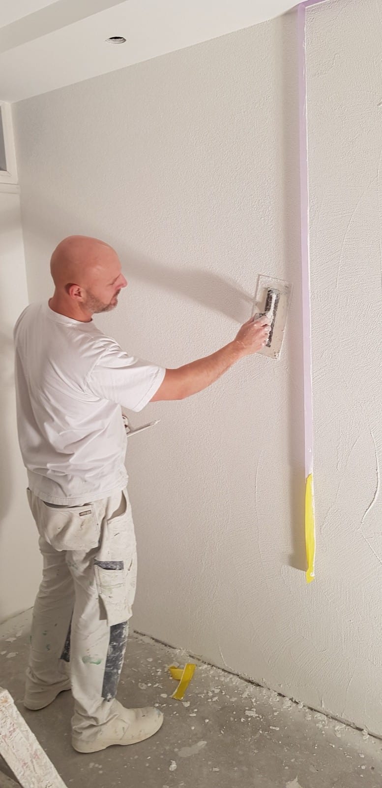 Stukadoor werkt de sierpleister met de spaan af, de korrelstructuur loopt over de hele wand door