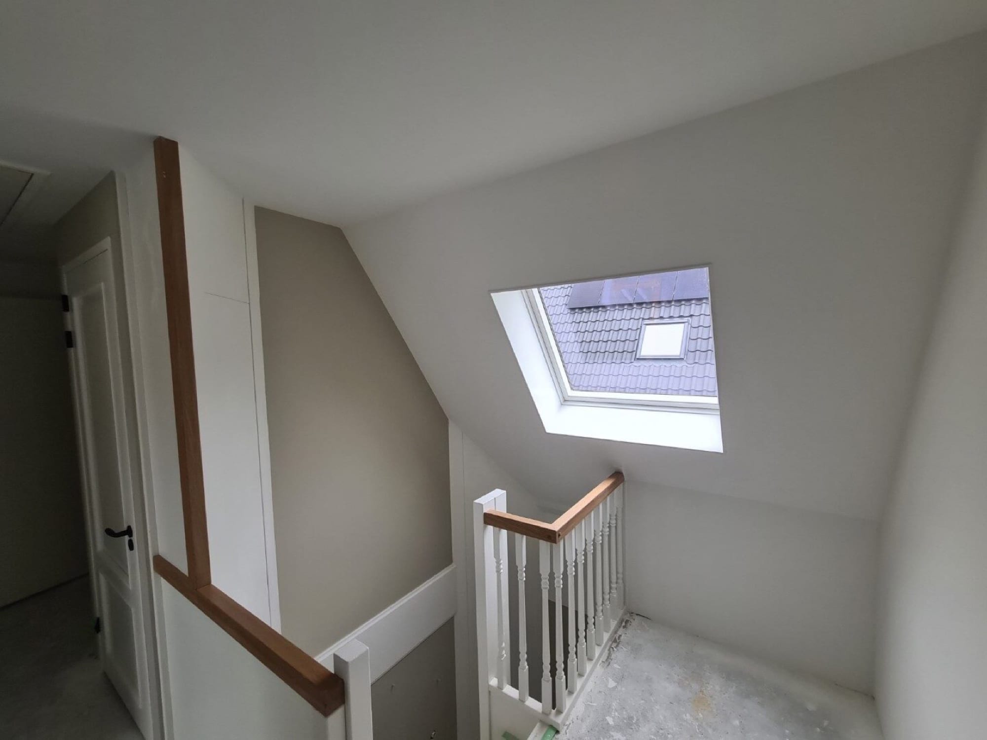 Overloop met dakraam en trap, strak wit stucwerk